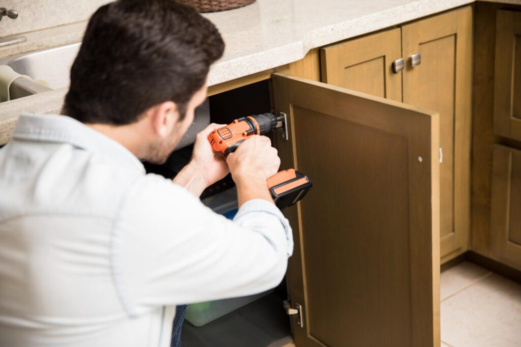 Man drilling a screw to secure a cabinet door 